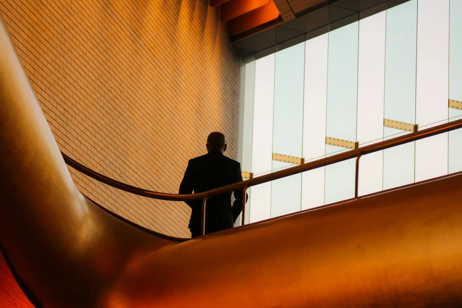An executive on a staircase inside a corporate lobby at dusk